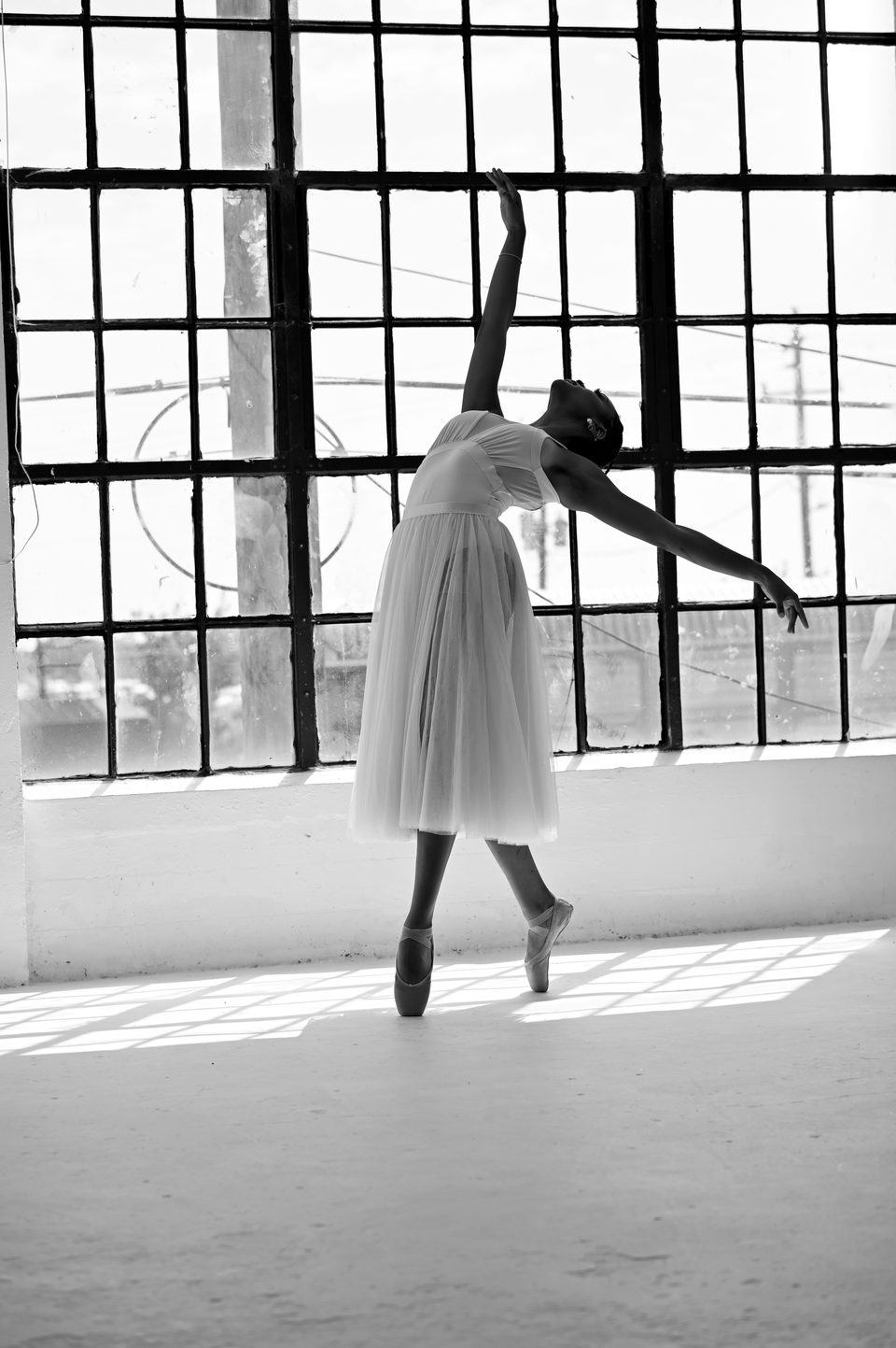 Arabesque on pointe against loft windows