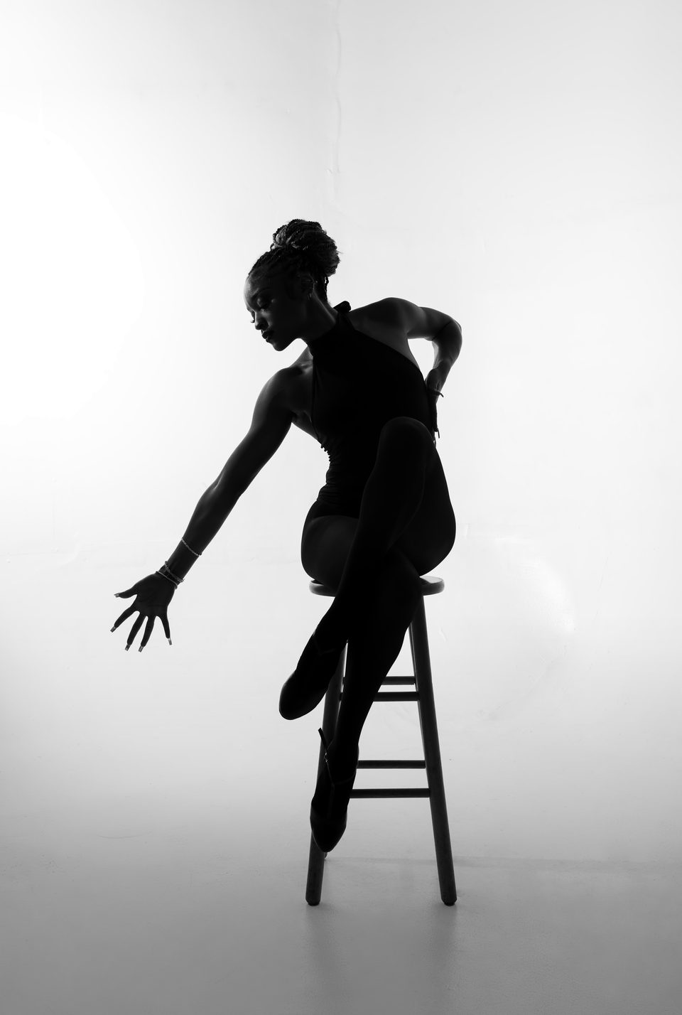 Silhouette, arms extended over a stool
